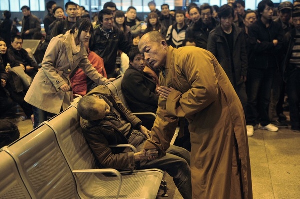 Một nhà sư đang cầu nguyện cho một người đàn ông đột tử bất ngờ khi đang đợi tàu ở nhà ga. Ảnh chụp tại Trung Quốc.